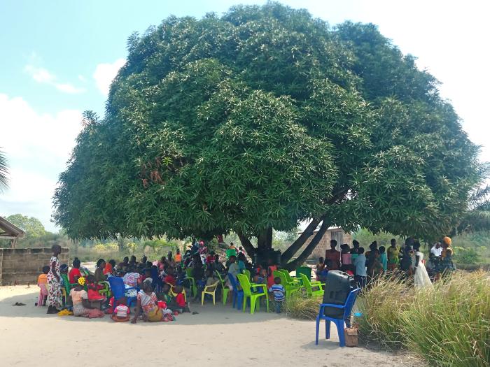 Washarika wa mtaa wa Tabora wakiwa wamekusanyika pamoja chini ya mti kwa ajili ya kupata chakula cha mchana mara baada ya kukamilika kwa ibada ya mavuno mtaani hapo.